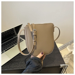 Close-up of khaki pebbled leather mini crossbody bucket bag with silver metal buckle