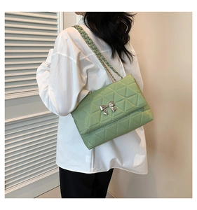 Detail of light green quilted PU leather bag with silver bow clasp and chain strap