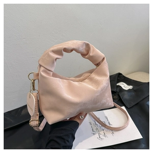 Detail of pink pleated handbag showing heart-shaped tag and soft gathered handle texture