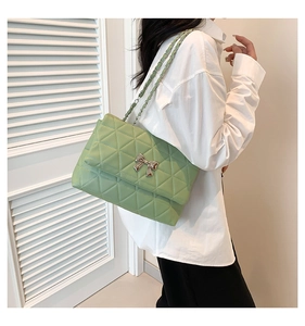 Close-up of light green quilted shoulder bag with silver bow buckle and chain strap