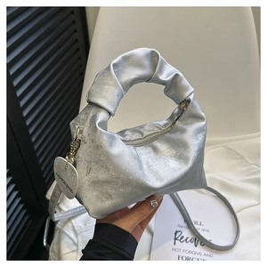 Close-up of silver pleated handle bag with metallic finish and heart charm detail