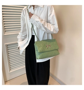 Detailed view of mint green quilted crossbody bag with a metal bow clasp and chain strap