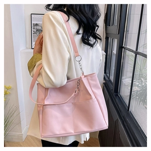 Pink matte leather tote bag detail with silver chain strap on a minimalist model