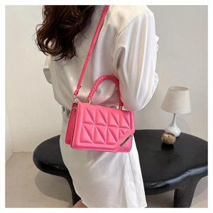 Sac bandoulière rose vif avec motif matelassé triangle et poignée tissée porté par un mannequin