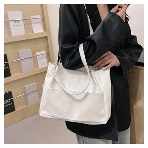 Detail of white PU leather tote bag featuring functional front pockets and silver hardware