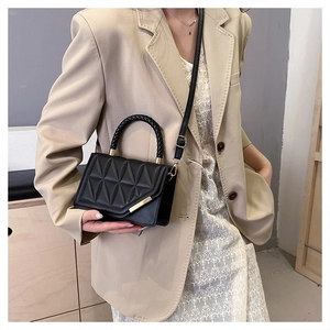 Détail du sac bandoulière noir matelassé avec poignée tressée et garnitures dorées