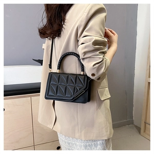 Détail du sac bandoulière noir avec matelassage géométrique et poignée tressée