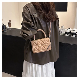 Sac bandoulière beige matelassé chic avec poignée tissée dans un café élégant