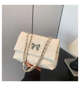 Detail of silver bow buckle and quilted cream leather on chain strap shoulder bag