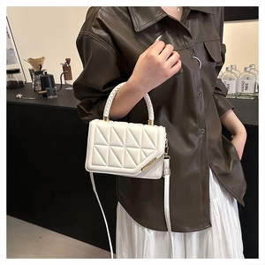 Détail du sac bandoulière en cuir blanc matelassé avec coutures géométriques et barre dorée