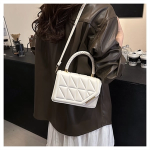 Détail du sac à bandoulière matelassé blanc avec coutures géométriques et poignée tressée