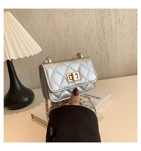 Close-up of silver quilted mini crossbody bag featuring a golden twist lock and chain strap