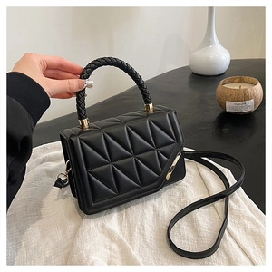 Détail du sac matelassé noir avec poignée tressée et garniture en métal doré chic