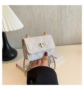 Close-up of beige quilted mini bag featuring golden twist lock and metal chain strap