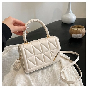 Détail du sac à main matelassé beige avec poignée tressée et accents dorés