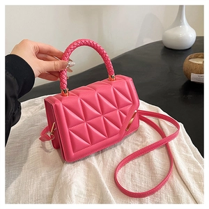 Détail du sac à main rose matelassé avec poignée tressée et fermoir doré géométrique