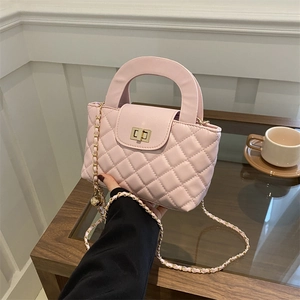Sac à main rose matelassé avec fermoir doré et bandoulière chaîne sur une table de café