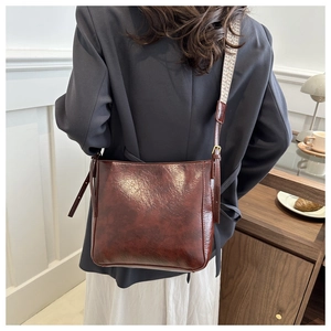 Détail du sac cabas en cuir marron foncé avec large bandoulière tissée beige élégante
