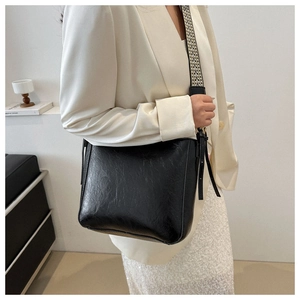 Vue détaillée du sac seau noir rétro avec une bandoulière tissée géométrique