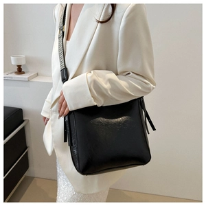 Détail du sac bandoulière noir minimaliste avec large sangle tissée pied-de-poule