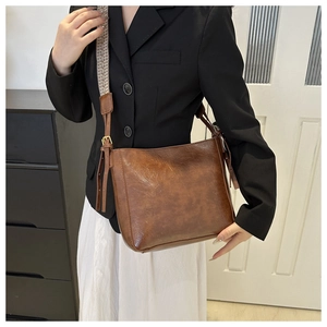 Détail du sac cabas vintage en cuir marron avec large bandoulière jacquard élégante