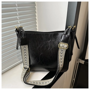 Détail du sac fourre-tout en cuir ciré noir avec bandoulière tissée à motifs chic