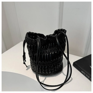 Detail of black pleated bucket bag with drawstring closure and glossy PU leather texture