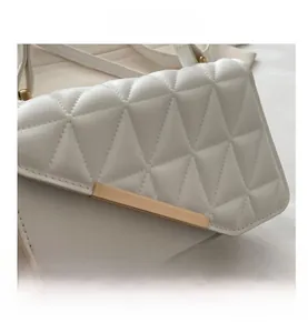 Close-up of white quilted handbag with triangle embossed texture and gold metal trim