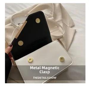 Close-up of white crossbody bag showing magnetic hardware buckle and black lining