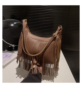 Détail du sac hobo en cuir grainé marron foncé avec de longues franges et boucle dorée