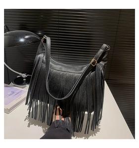 Détail d'un sac à bandoulière en cuir grainé noir avec de longues franges sur les côtés