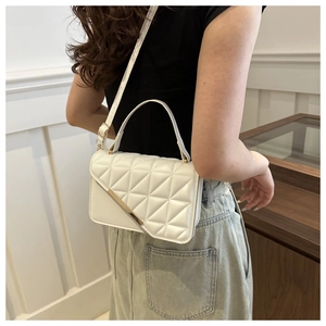 Detailed view of white quilted faux leather handbag with gold metal edge and fine strap