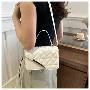 Detail of white quilted crossbody bag with golden metal trim and sleek leather texture