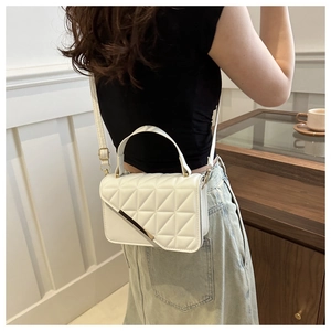 Close-up of white quilted crossbody bag with gold hardware and adjustable strap
