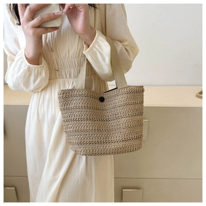 Détail du sac cabas en paille tissée avec poignées en tissu beige et boucle noire de fermeture