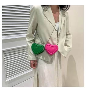 Detail view of mini heart chain bags in vibrant green and rose pink with gold text