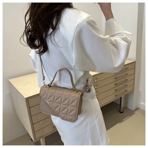 Detailed close-up of khaki quilted crossbody bag with gold metal trim and handle