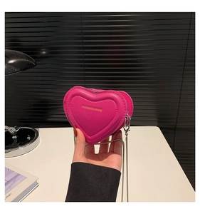 Close-up of mini rose pink heart-shaped leather bag with gold text and silver chain
