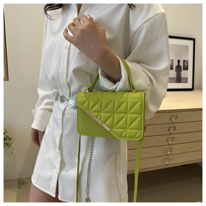 Detail of neon green quilted crossbody bag with silver metal bar and elegant strap