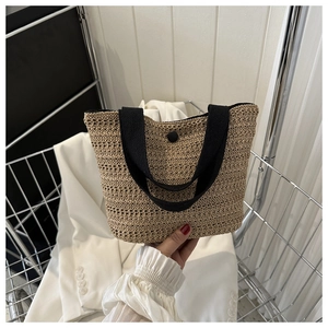 Gros plan du sac fourre-tout en paille tissée avec poignées noires et bouton-pression