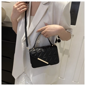 Detail of black quilted crossbody bag featuring gold hardware and a top handle strap