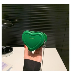 Detail of green heart-shaped mini bag with gold fashion lettering and metal chain strap