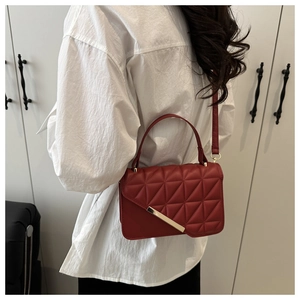Detail of dark red PU leather handbag with geometric triangle quilting and gold metal buckle