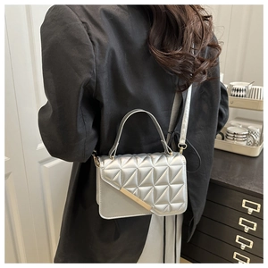 Silver quilted crossbody bag with golden metal trim shown from a back carry view