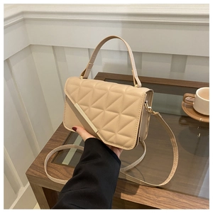 Detailed close-up of beige quilted crossbody bag with golden hardware and chain strap