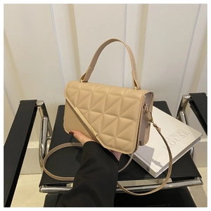 Detail of beige quilted crossbody bag with golden metal trim and sleek leather texture