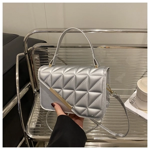 Detail of silver metallic quilted handbag with gold bar and geometric triangle pattern