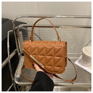 Close-up of brown quilted handbag featuring diamond texture and gold metal trim