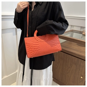 Detailed macro of bright orange crocodile-embossed handbag with round cut-out handles