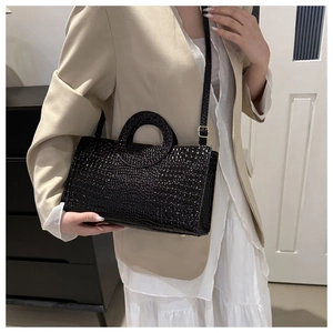 Detail of black croco-embossed texture on a large capacity stylish lady's shoulder bag